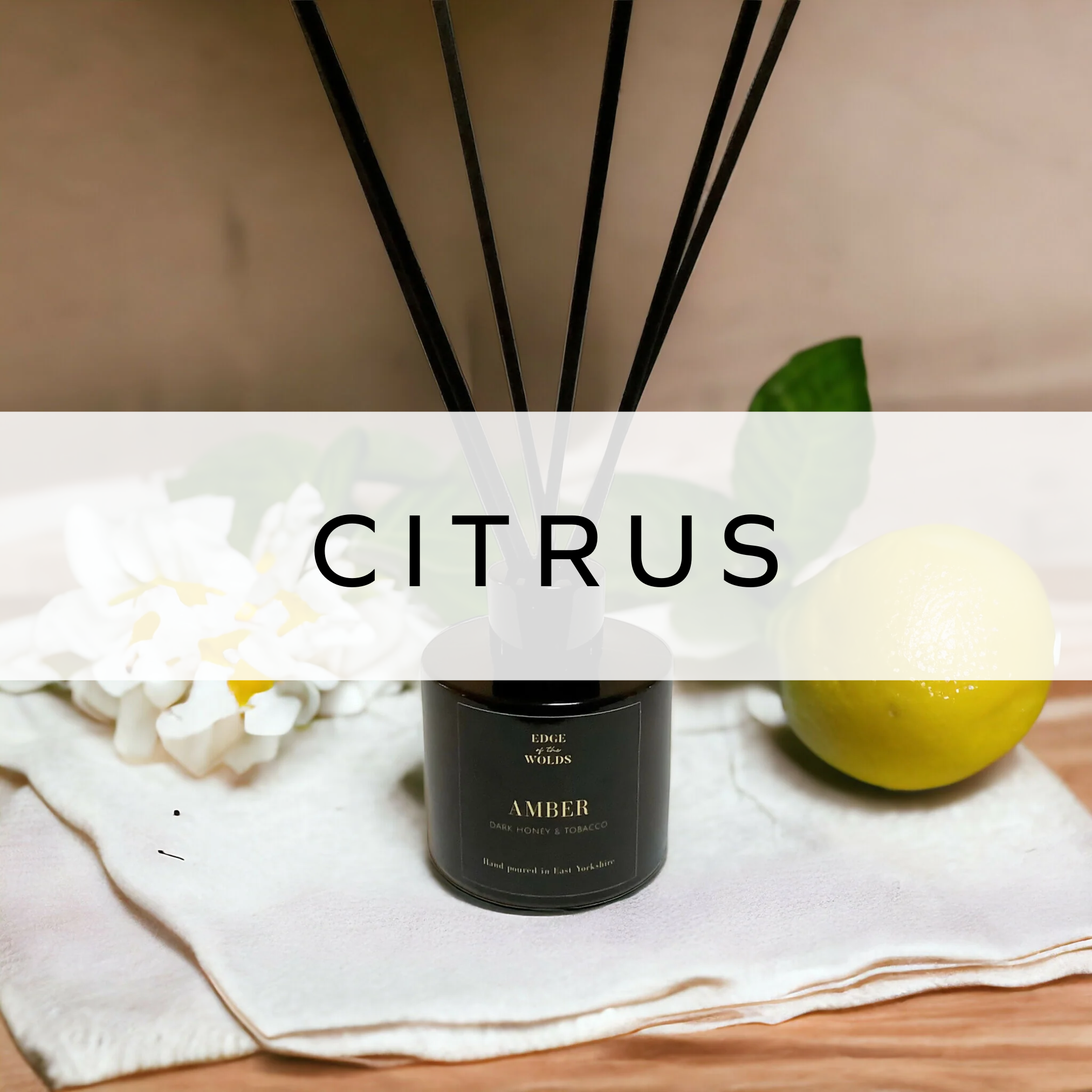 A reed diffuser with elegant sticks, placed in front of a fresh lemon, highlighting a bright and zesty citrus-inspired ambiance.