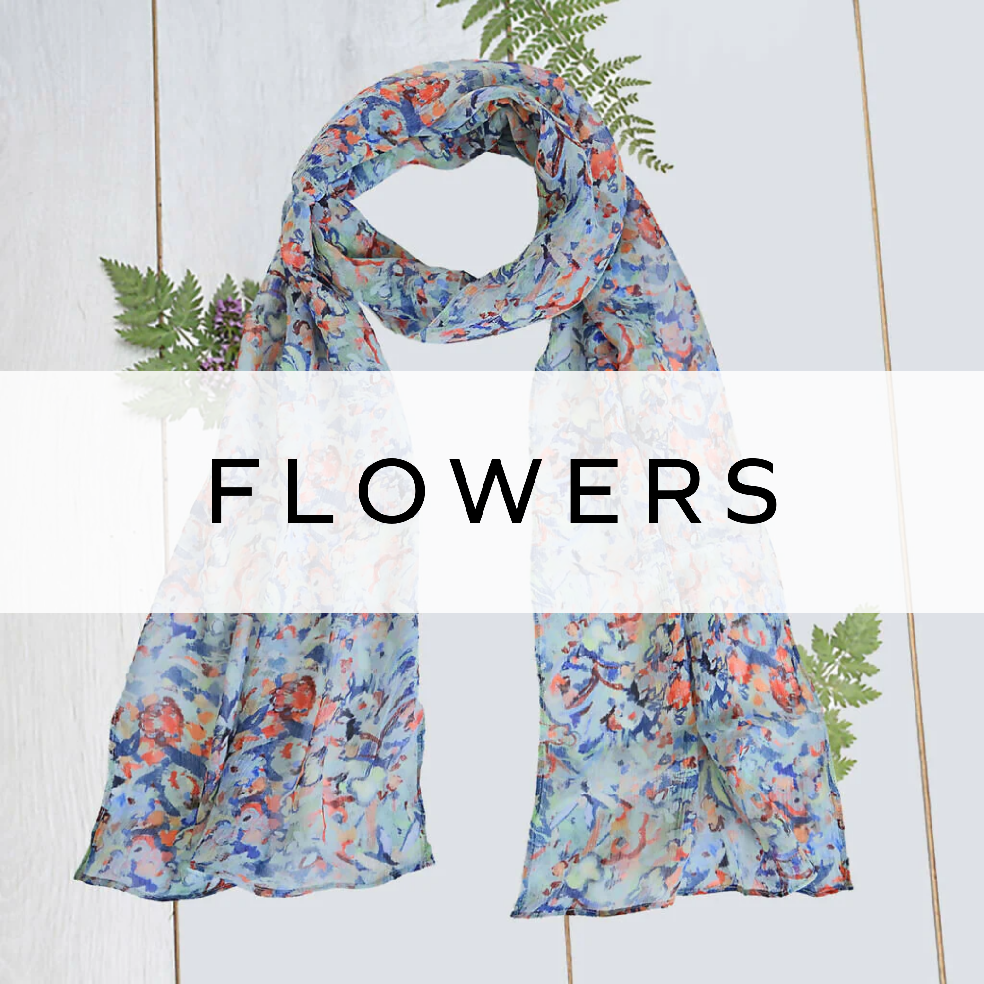 Blue silk scarf with a vibrant orange flower pattern, draped to show its soft texture and elegant floral design.