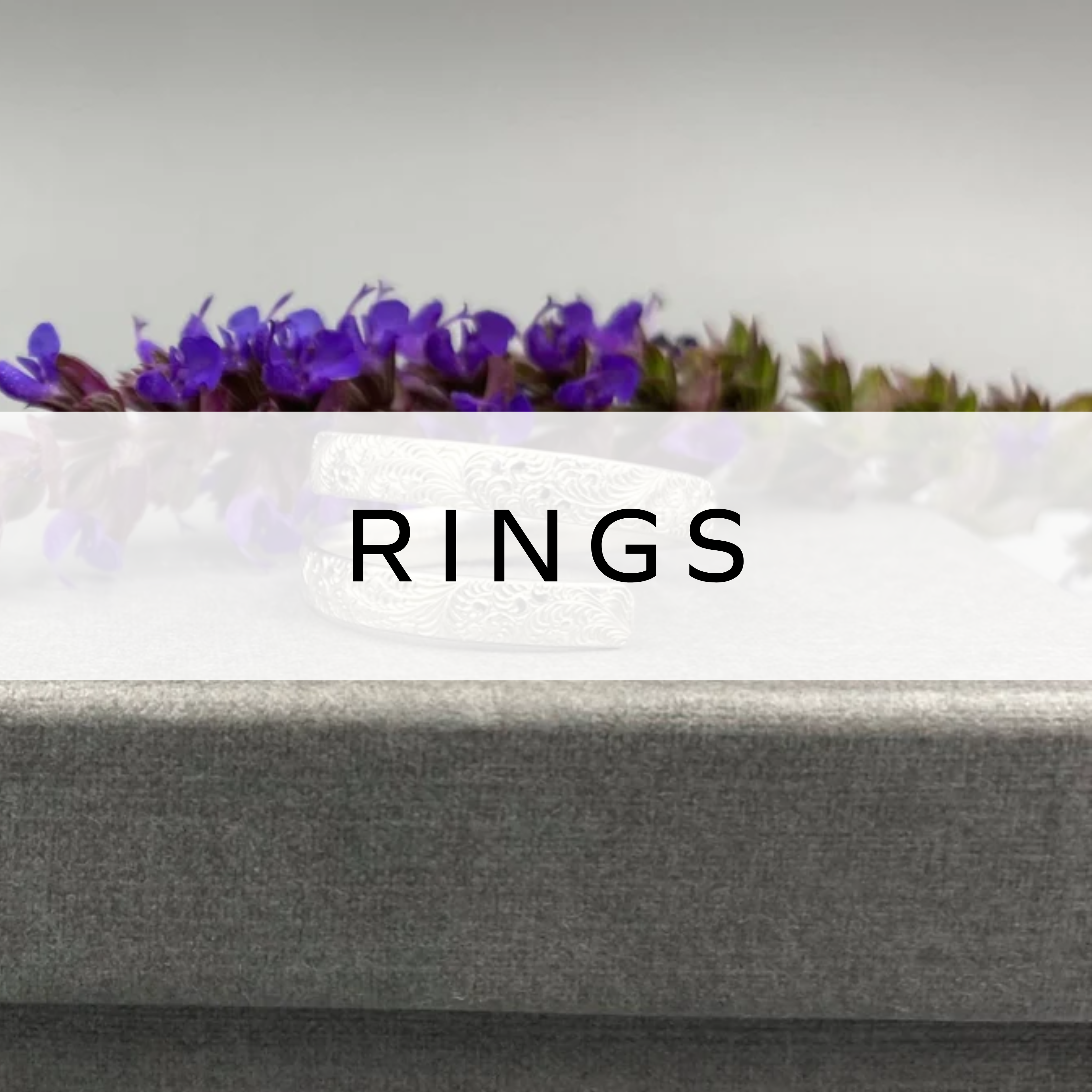 Silver ring displayed in front of soft-focus flowers, showcasing its elegant, minimalist design.
