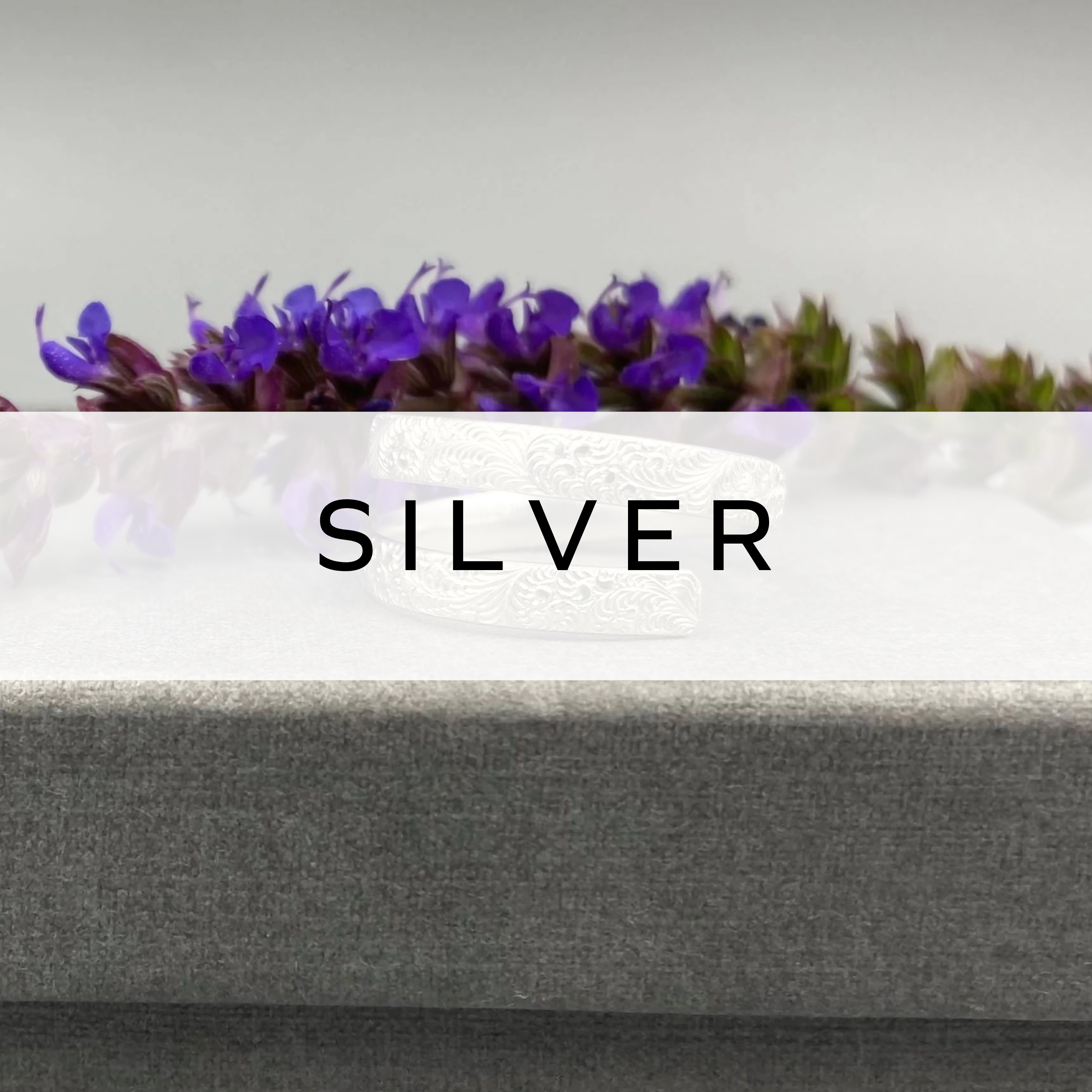 Silver ring displayed in front of vibrant purple flowers – elegant and timeless design.