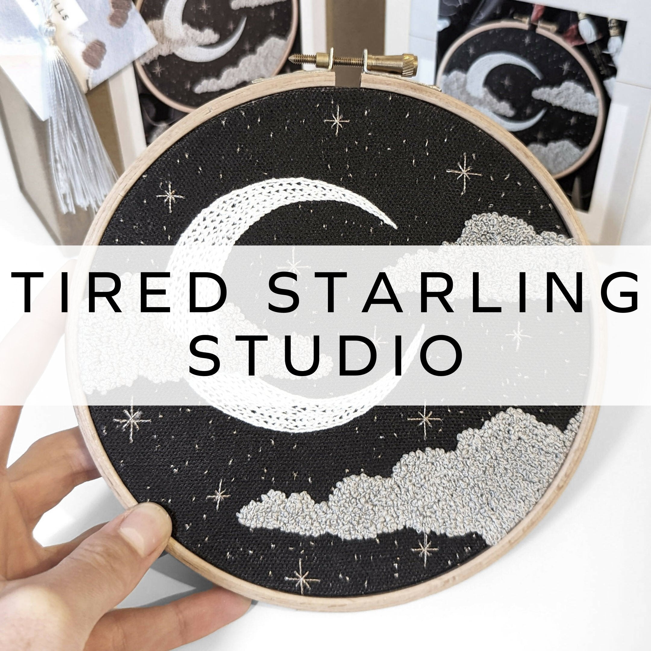 Embroidery hoop featuring a celestial design with stars, a moon, and clouds, stitched in a greyscale color palette, creating a dreamy and atmospheric piece.