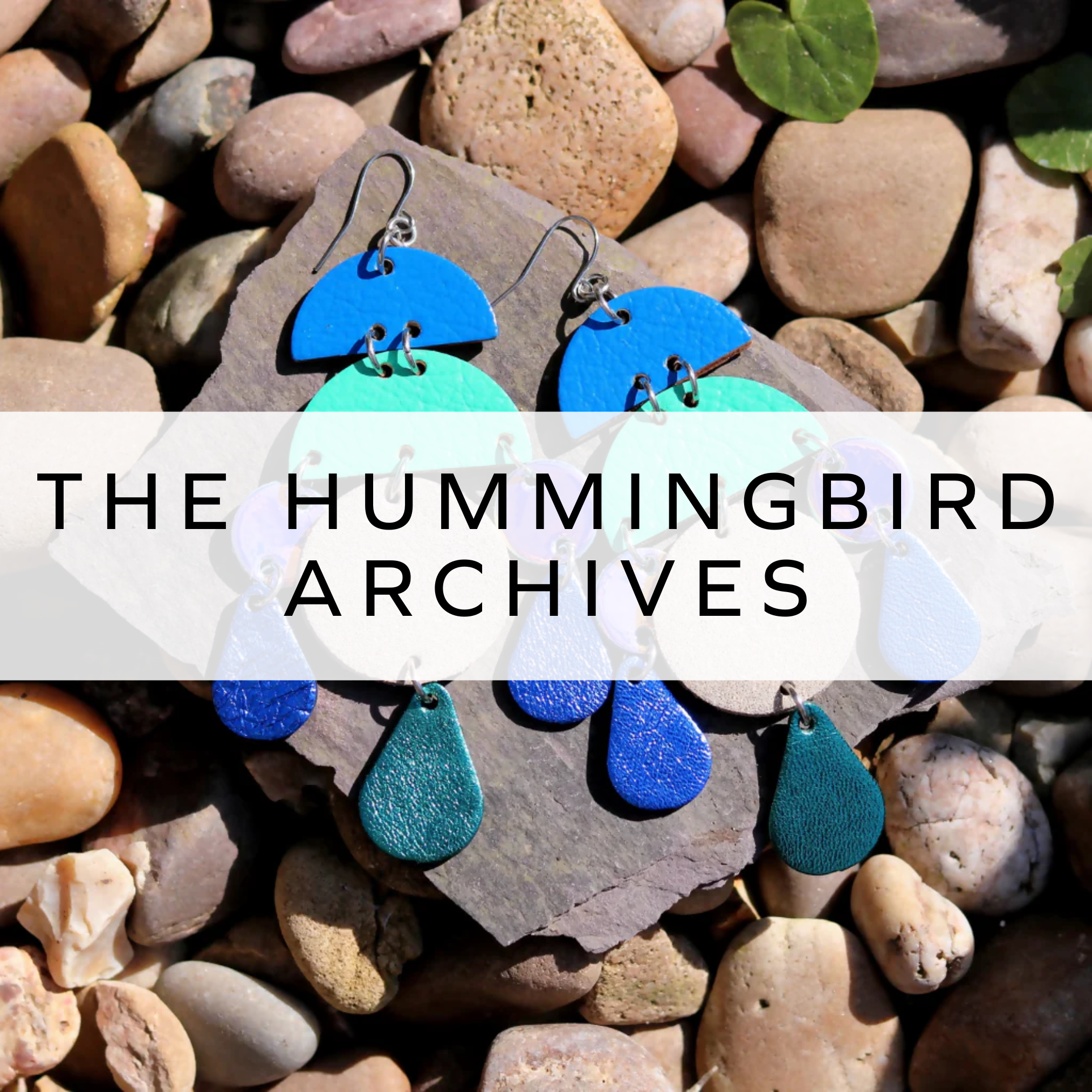 Blue and green statement earrings displayed on rocks.