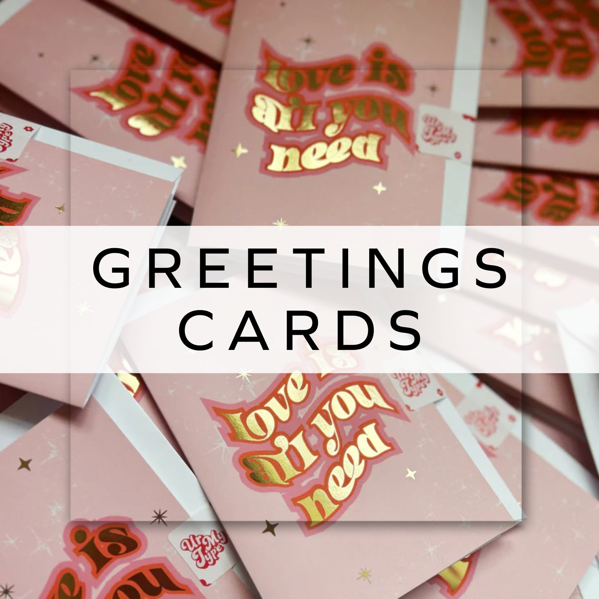 A pile of pink and gold cards with the text "love is all you need".