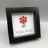 A bouquet of red hearts in a small black frame.