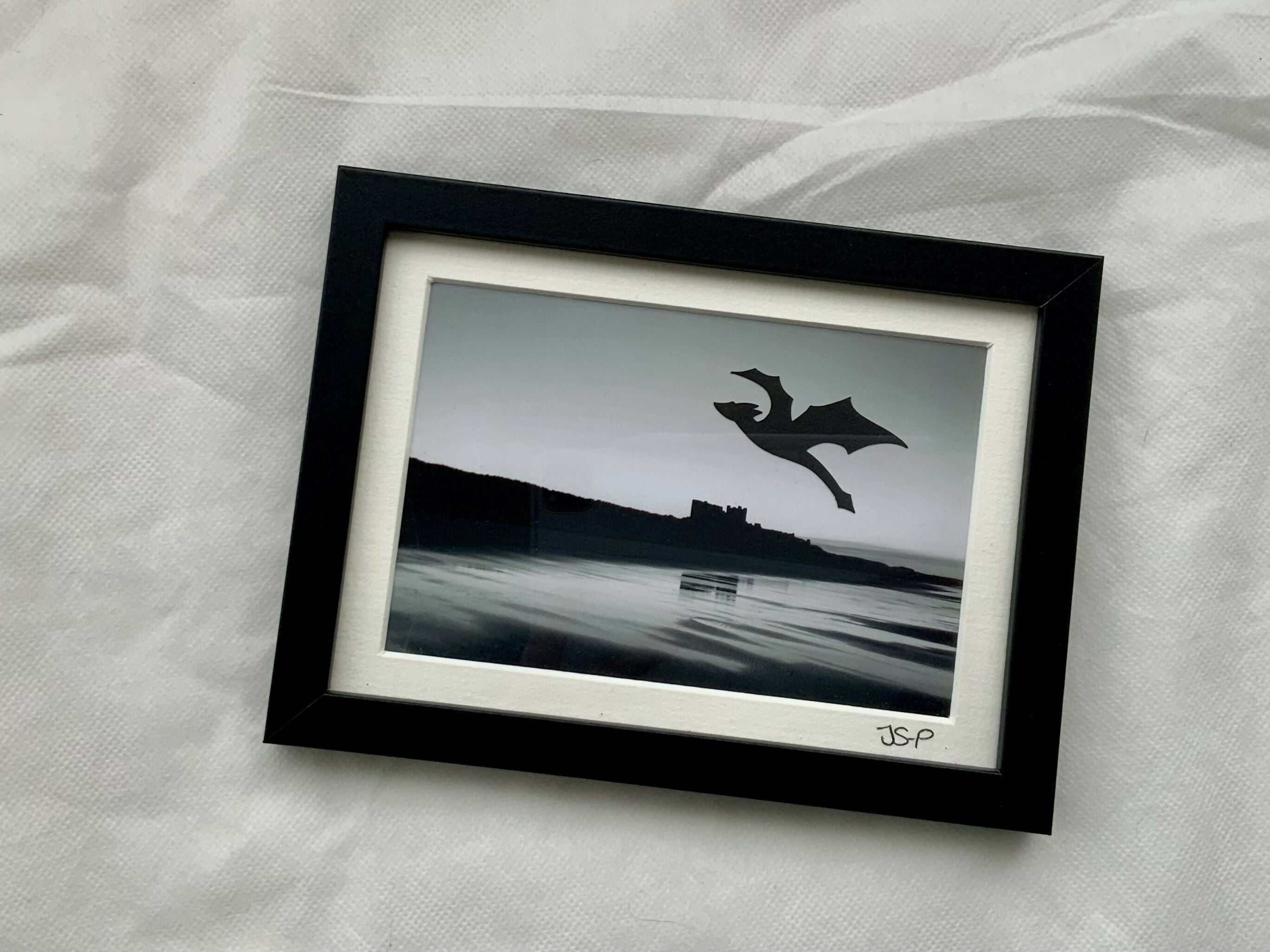 Black and white image of a dragon flying over a photograph of water.