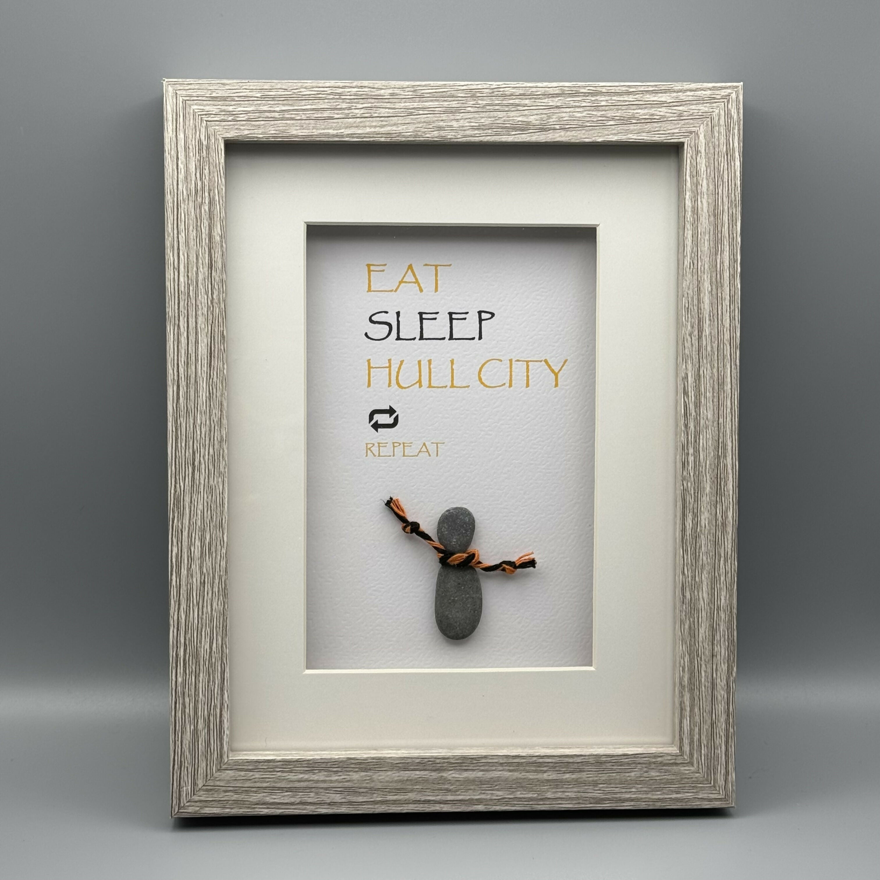 Pebble art picture with an orange and black scarf and the typography, 'EAT SLEEP HULL CITY REPEAT'.