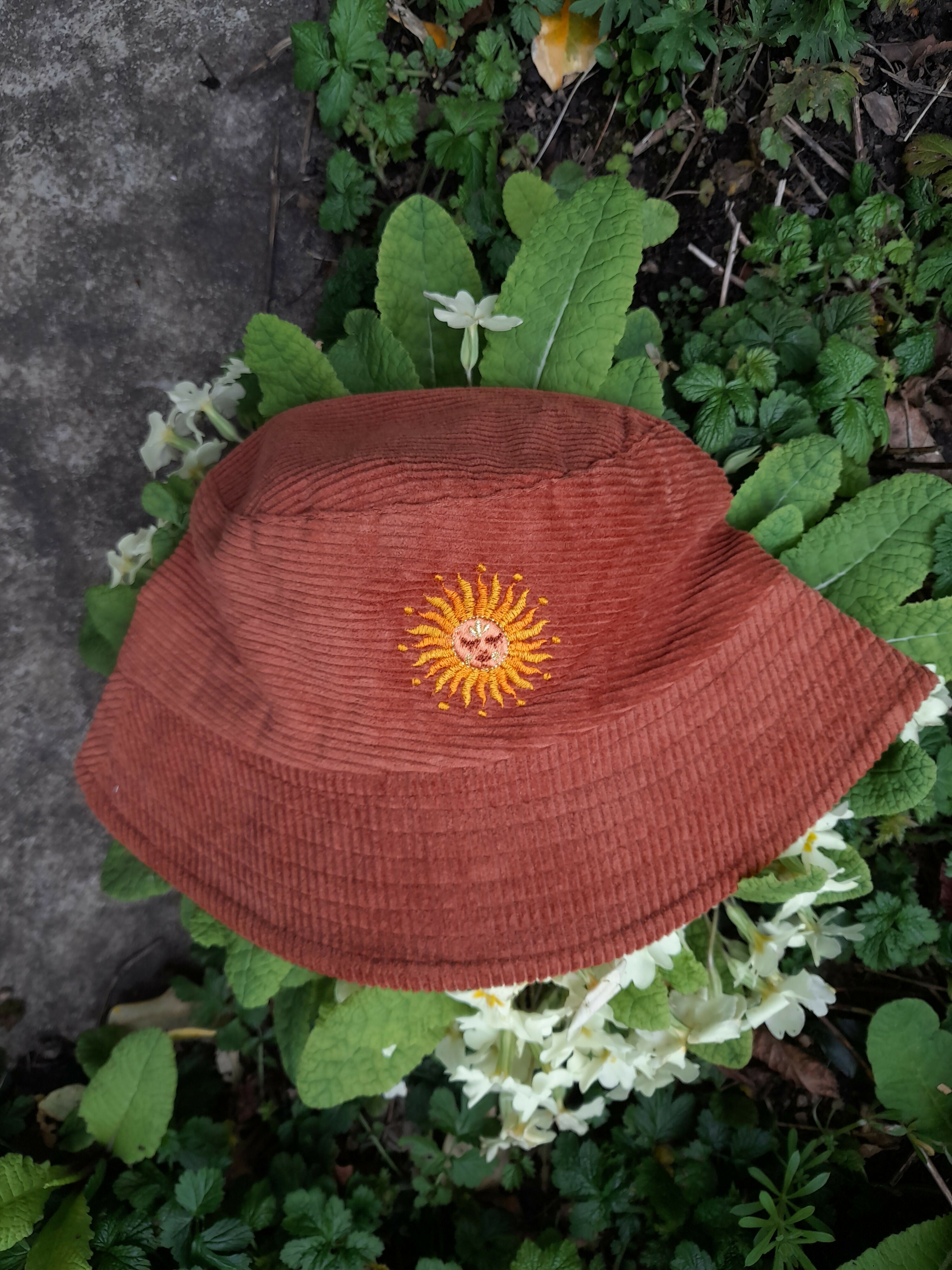 Burnt orange cord bucket hat with sun embroidery.