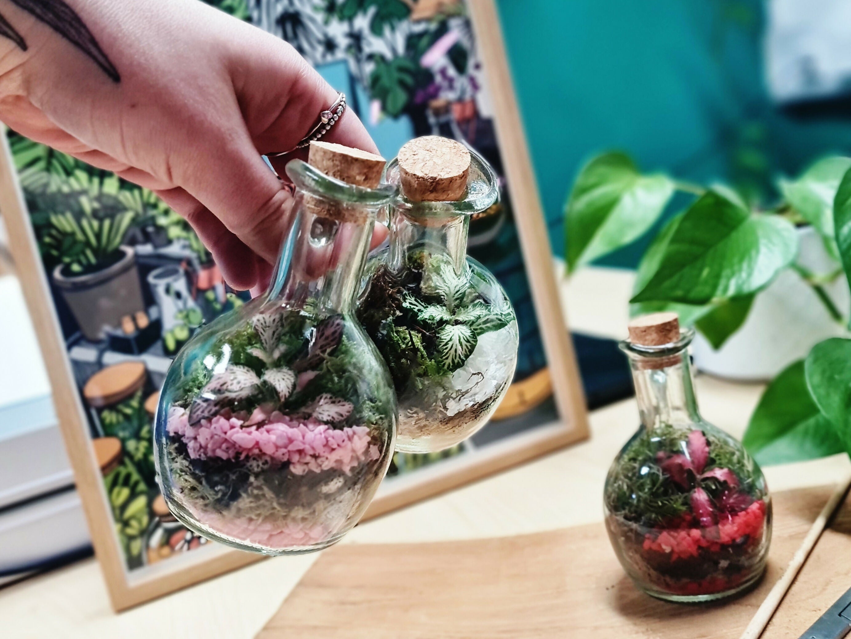 Glass oil pourer bottle with coloured stones and plants inside.