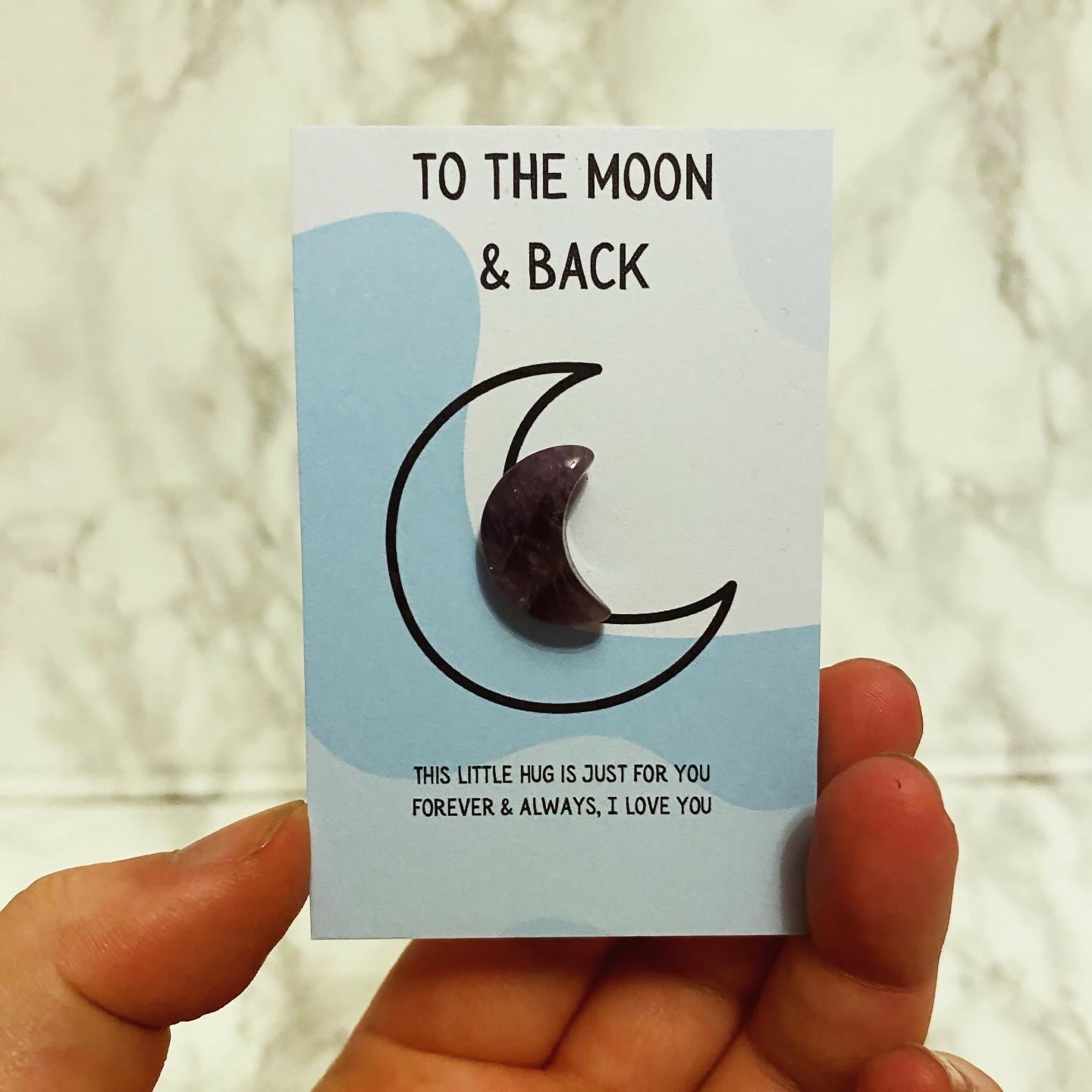 crystal design pebble in the shape of a moon on a card.