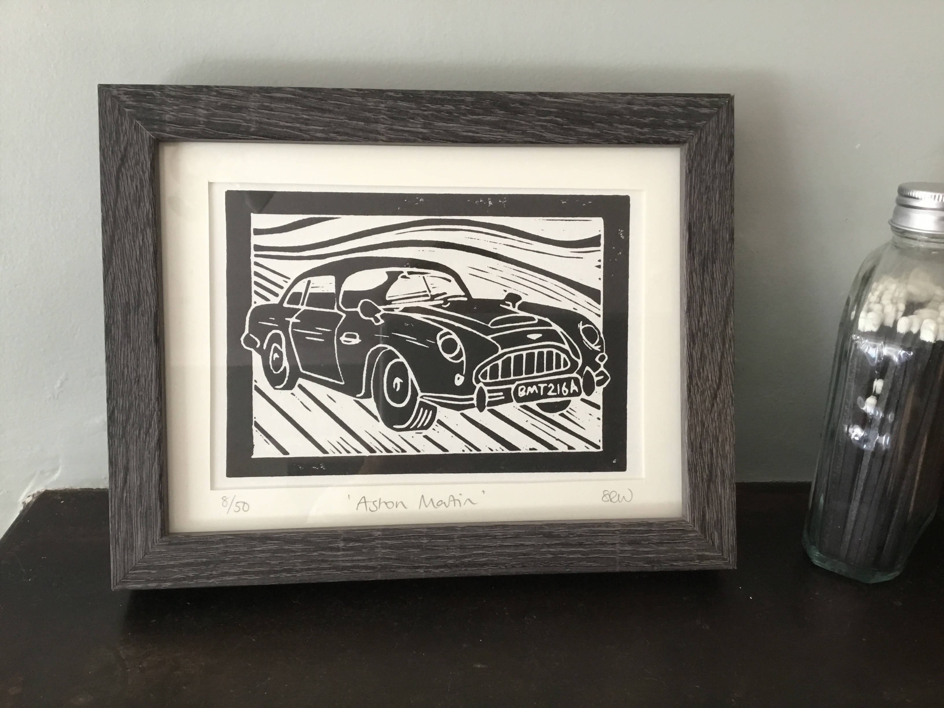 Black and white print of an old Aston Martin car.