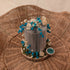 Miniature Blue Floral Arrangement on Wooden Slice.