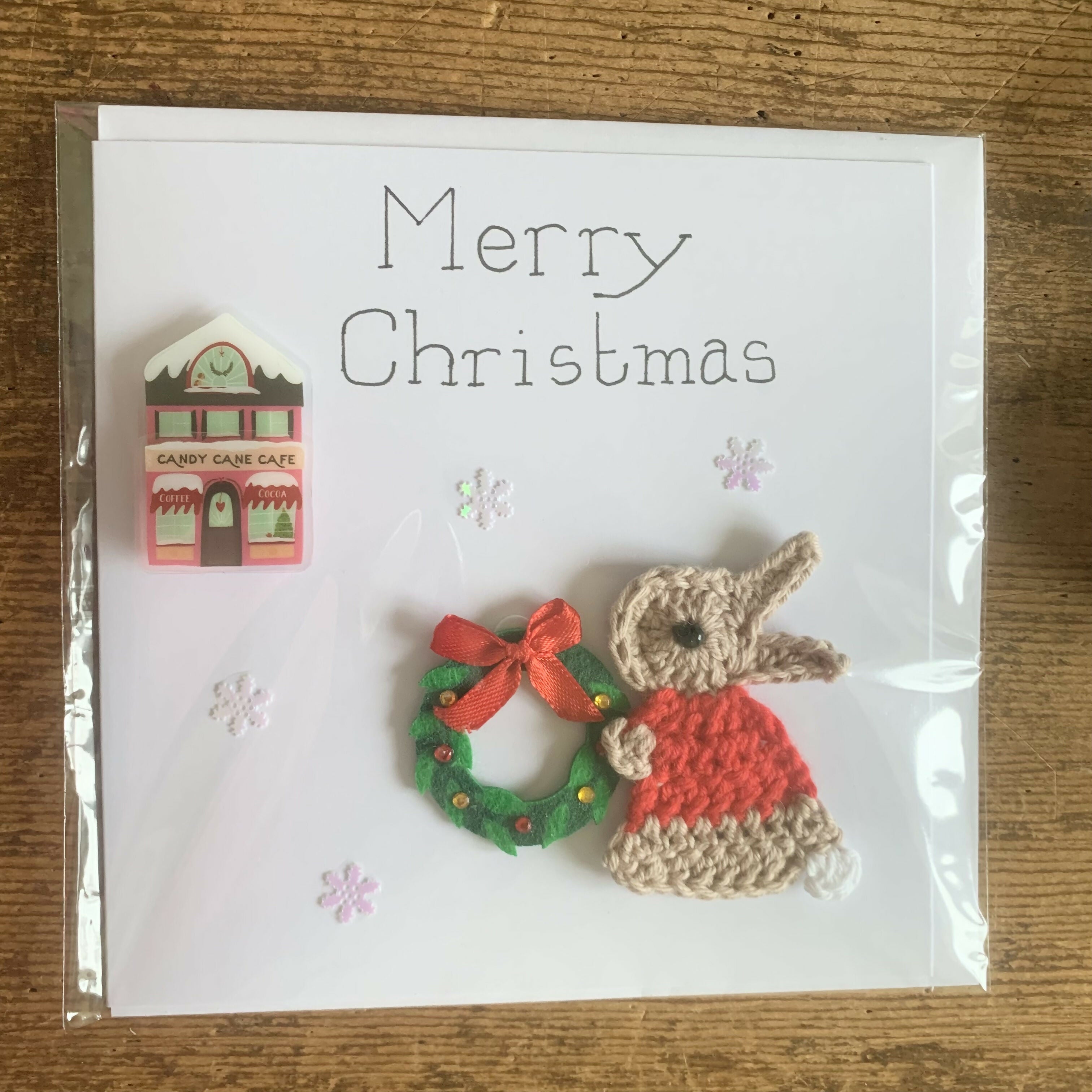 Christmas Card with Crocheted Rabbit Decorating a Shop with a Wreath
