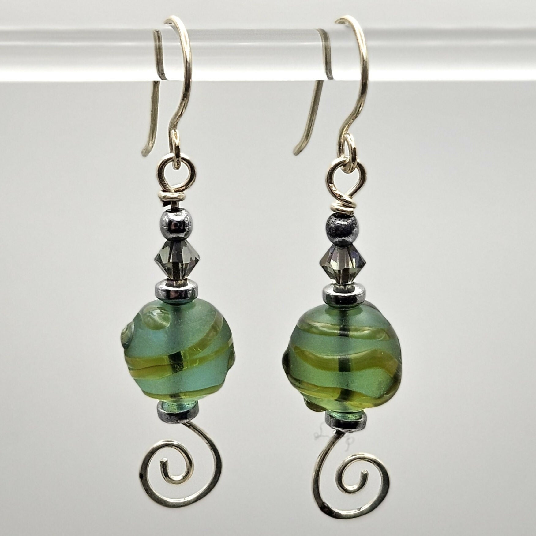 HAND LAMPWORKED GLASS SWIRL EARRINGS, WITH AN ETCHED FINISH, HAND FORMED STERLING SILVER WIRE WORK, STERLING SILVER EAR WIRES AND SWAROVSKI CRYSTALS.