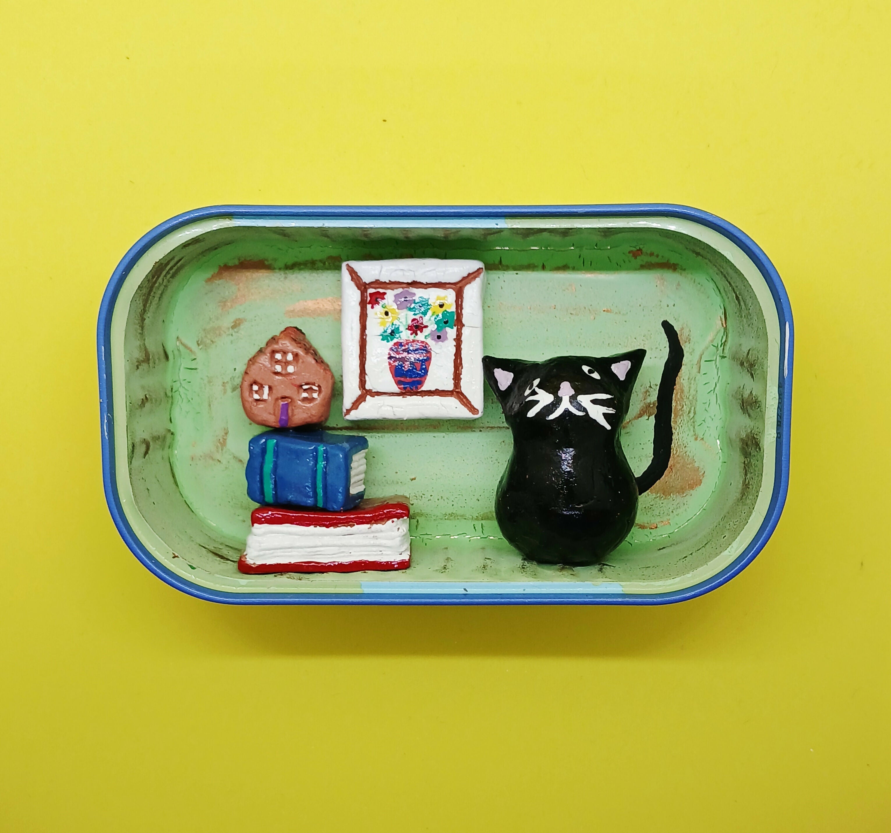 Black Cat with Books and Picture in a Tin