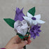 bouquet of paper flowers featuring a white daisy, purple tulip, purple gerbera, white patterned rose and three dark green folded origami leaves