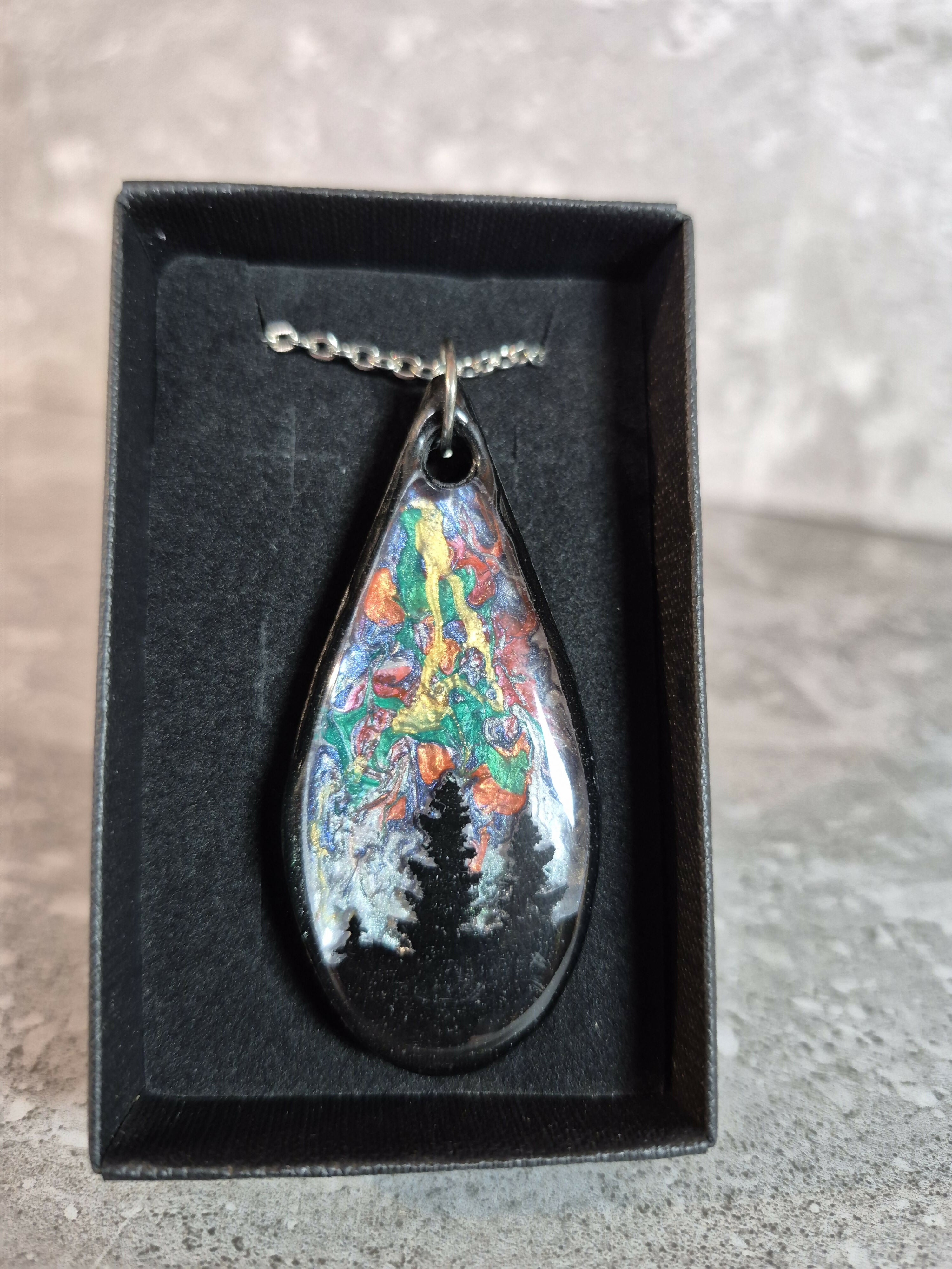 Unique, Hand Crafted, Teardrop Pendant Showing Black Silhouetted Pine Trees Against a Multicoloured Abstract Back Ground Sky