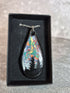 Unique, Hand Crafted, Teardrop Pendant Showing Black Silhouetted Pine Trees Against a Multicoloured Abstract Back Ground Sky