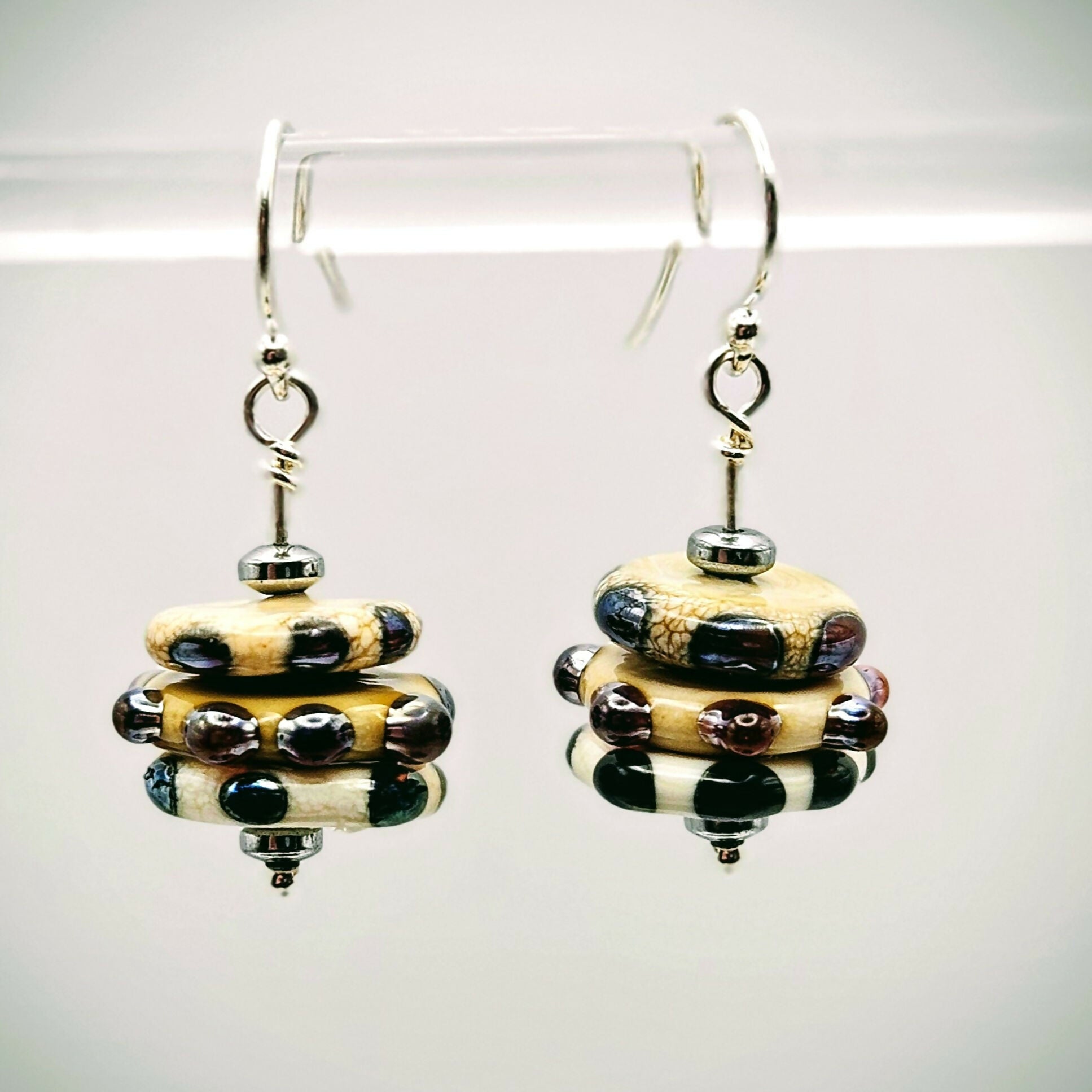 HAND LAMP WORKED GLASS STACKED EARRINGS, WITH DOTS AND SPOTS, STERLING SILVER EAR WIRES AND HEMATITE ACCENT BEADS.