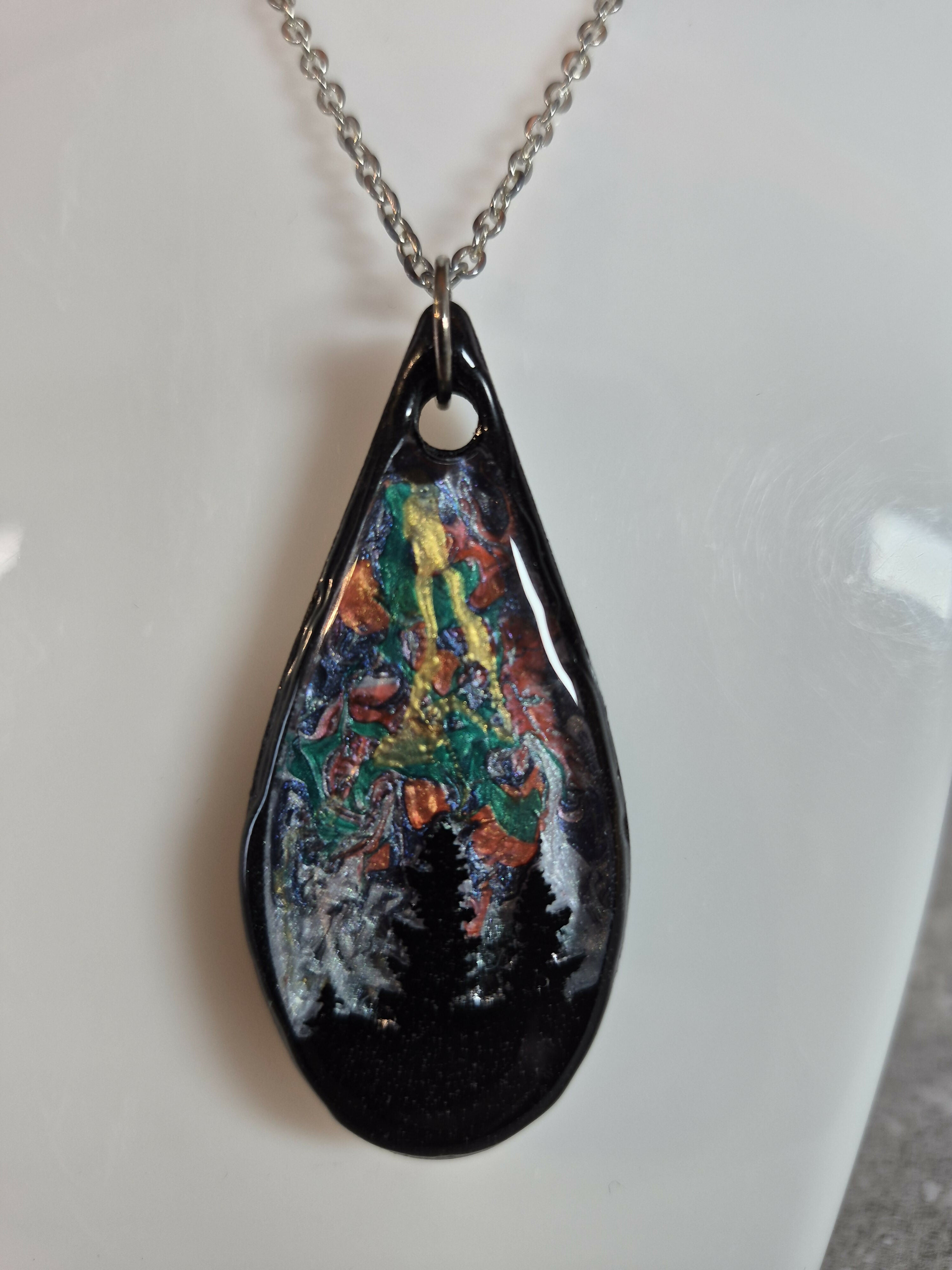 Unique, Hand Crafted, Teardrop Pendant Showing Black Silhouetted Pine Trees Against a Multicoloured Abstract Back Ground Sky