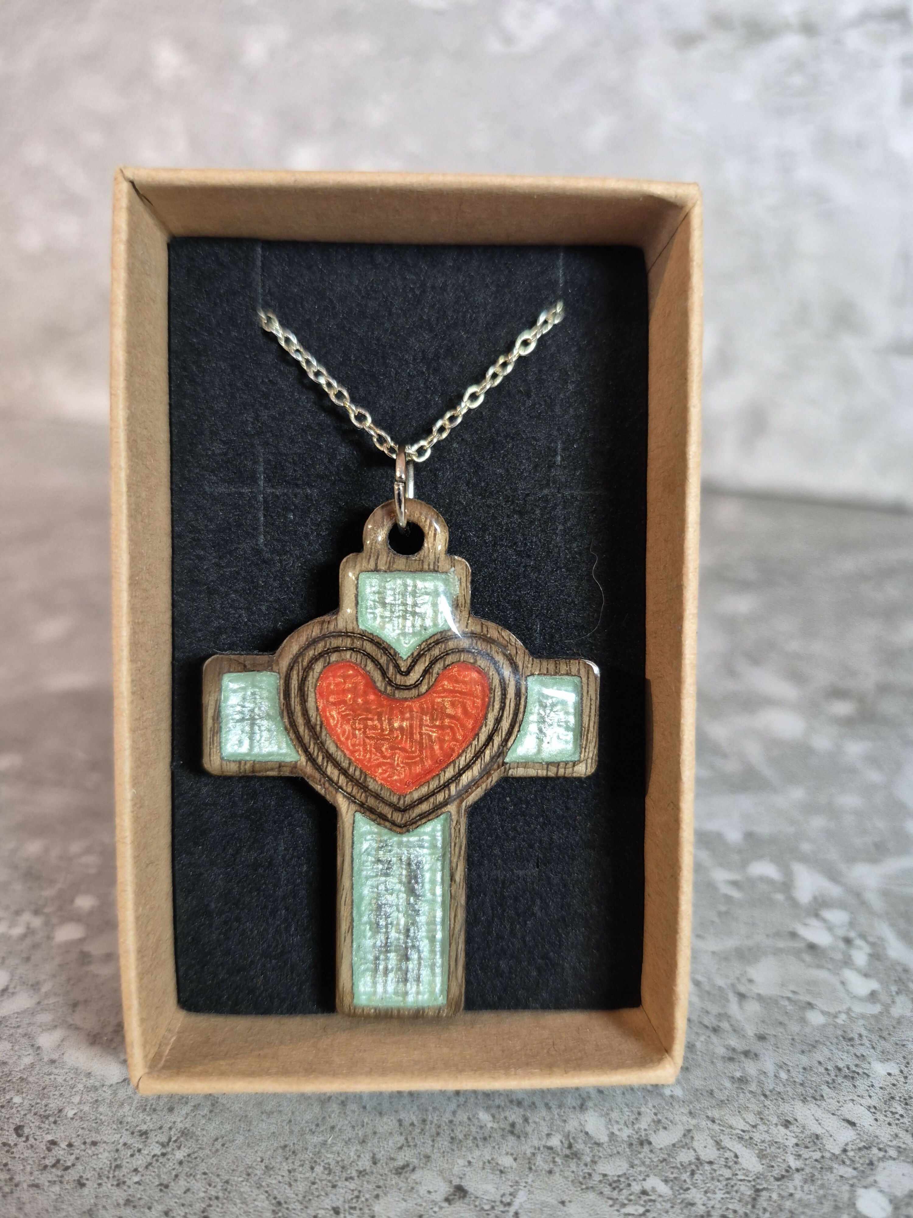 Handcrafted and engraved walnut veneered cross with a heart pendent.