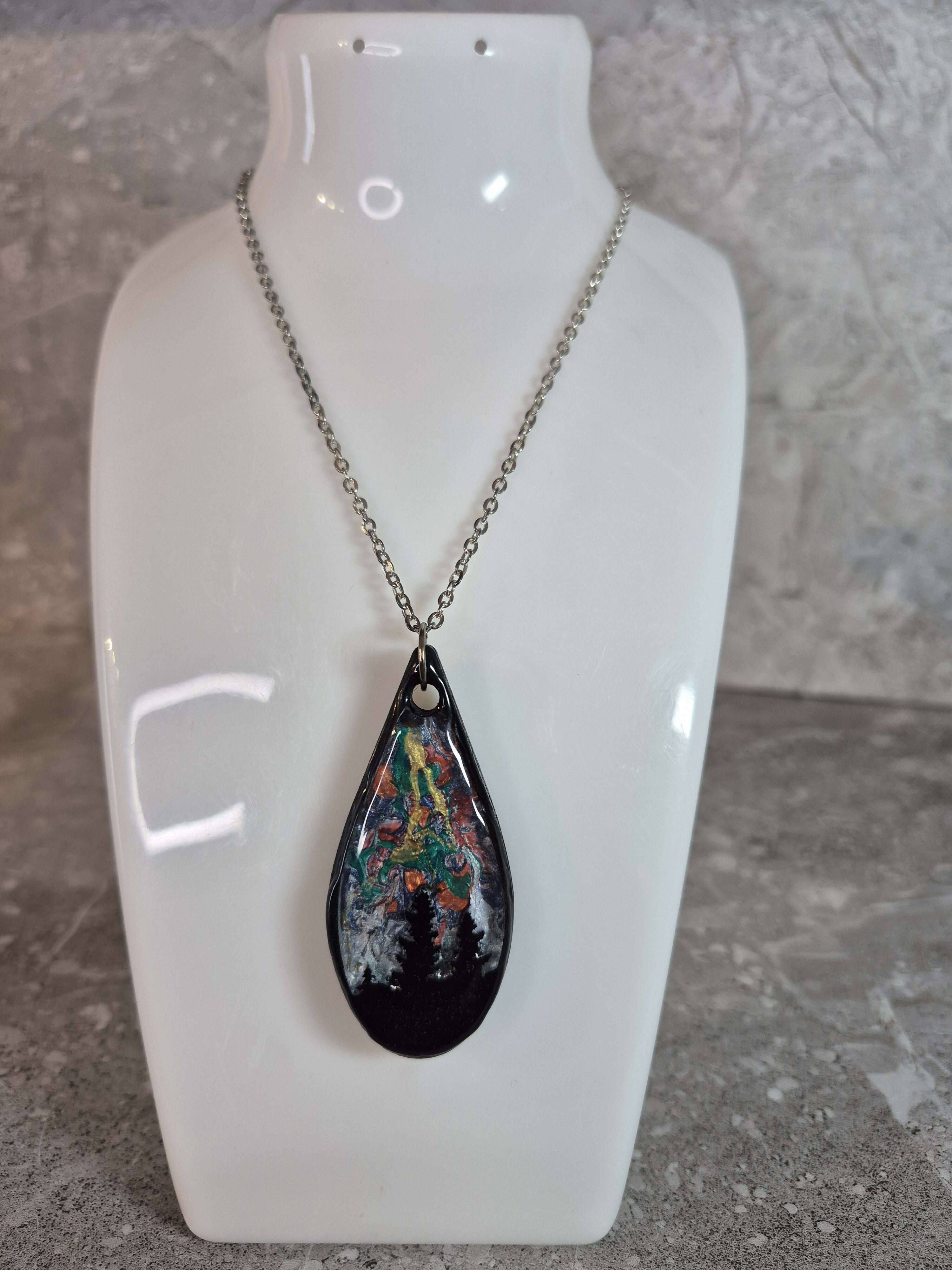 Unique, Hand Crafted, Teardrop Pendant Showing Black Silhouetted Pine Trees Against a Multicoloured Abstract Back Ground Sky