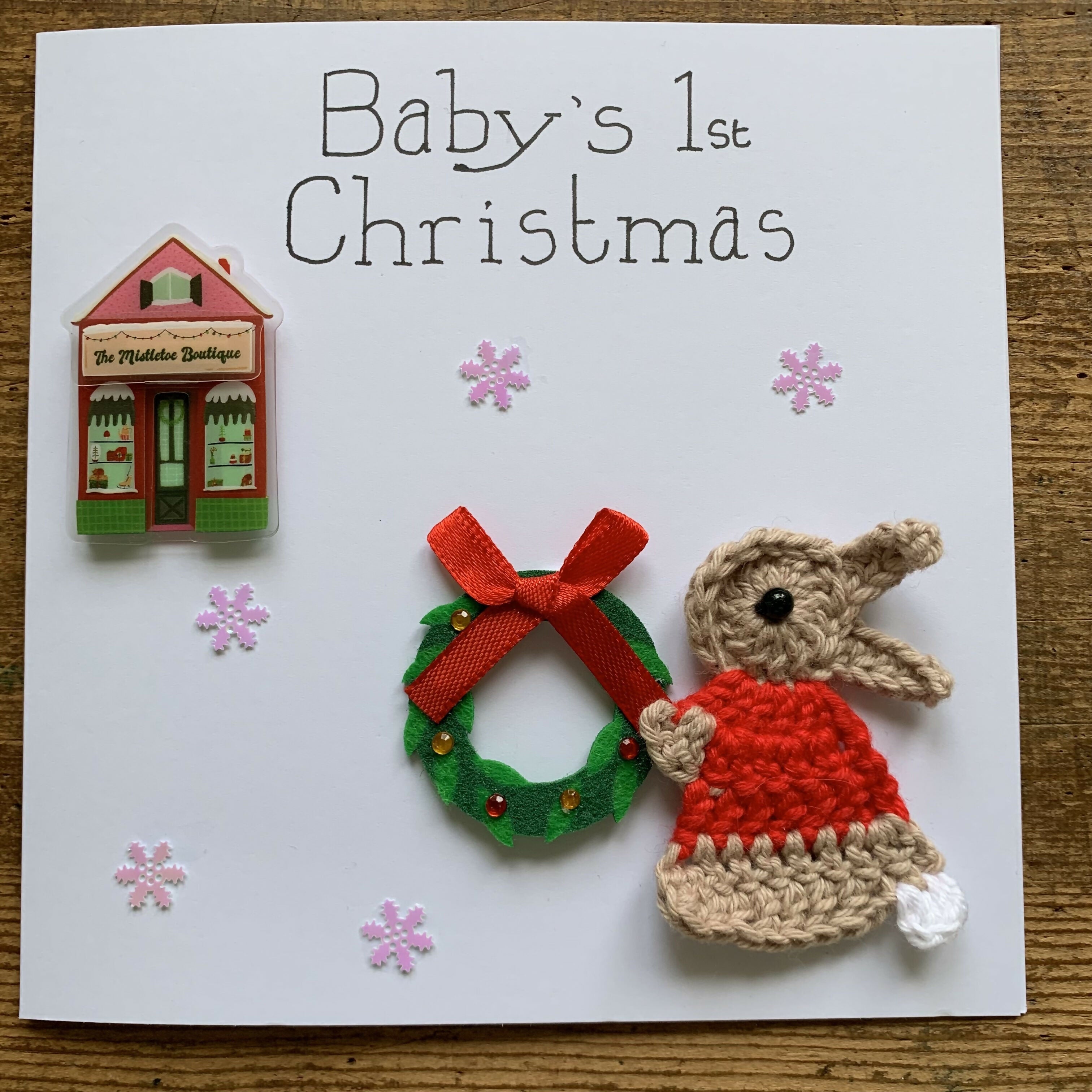 Christmas Card with Crocheted Rabbit Decorating a Shop with a Wreath